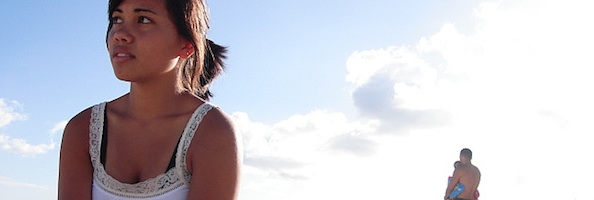 Young woman sitting alone outdoors, looking away